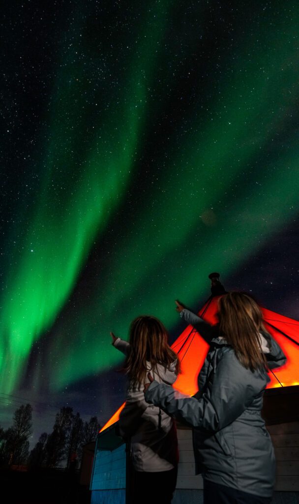 Two women pointing to northern lights