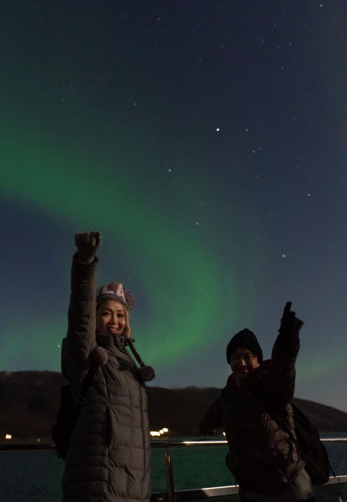 Two people posing with northern lights in the background