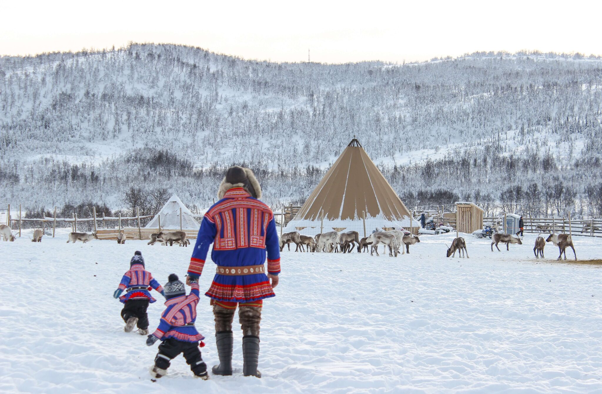 Sami man with two kids and lavvo in the background