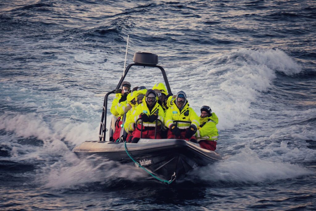 A group of people wearing bright yellow suits on a Rigid Inflatable Boat tour in Skjervøy, north Norway