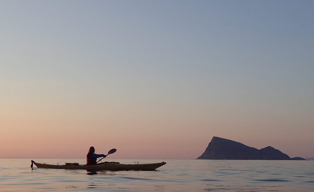 Kayaking in the summer in the sunset with a mountain in the background