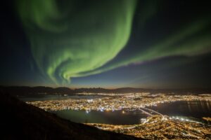 Vivid green aurora over illuminated city center of Tromsø