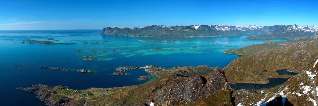 Clear blue waters with green mountains in the background in Senja, northern Norway.