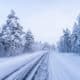 Snow-covered road through a winter forest seen from a bus between Tromsø and Rovaniemi