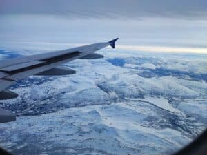 View from an airplane window showing the right wing above snowy mountains near Tromsø, Northern Norway