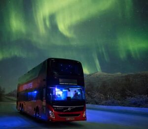 Aurora Express double-deck red bus from Best Arctic stopped on a snowy road at night under the northern lights