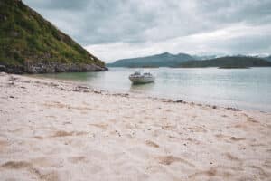A boat by the Sommarøy white beach, during summer with green mountains